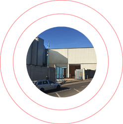 Industrial facility exterior framed by a bold red circular design